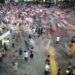 a colorful photo of a busy street, masses of people blurred in motion