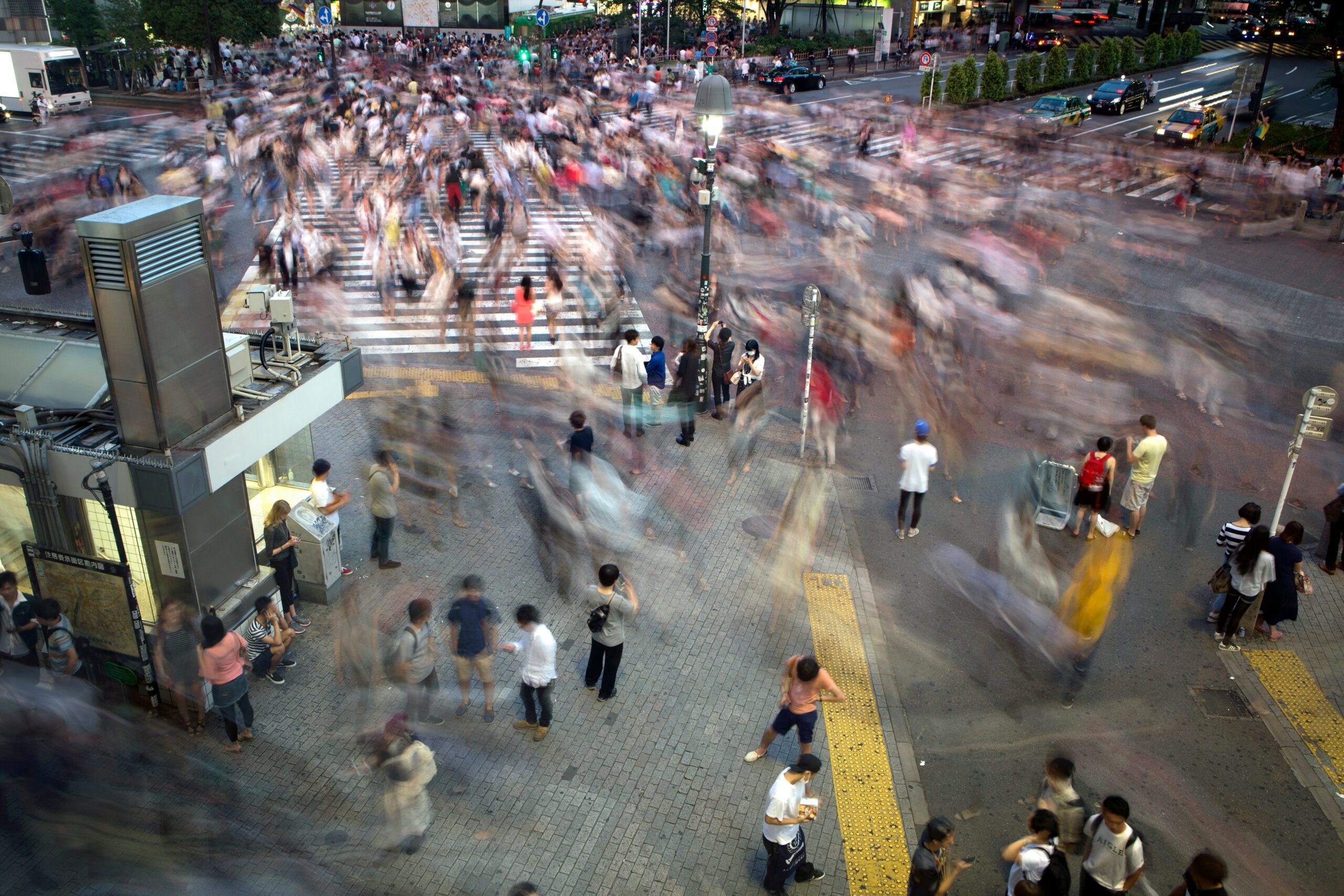 a colorful photo of a busy street, masses of people blurred in motion
